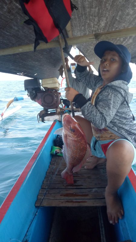 Person catching a fish from Balian fishing boat